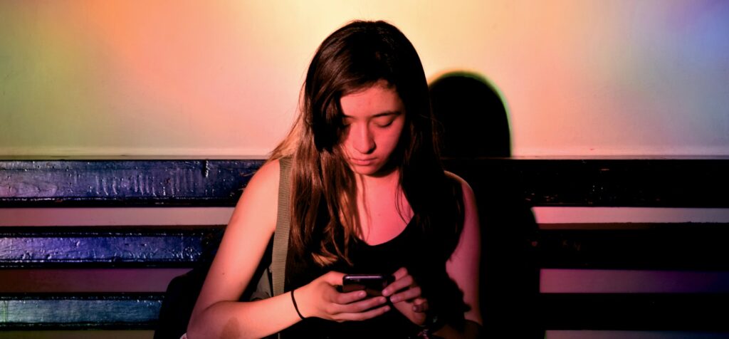 Young woman is looking down at a smartphone in her hand.